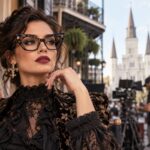 Stylish New Orleans arts professional wearing dramatic architectural cat-eye eyewear on a cinematic French Quarter film set.